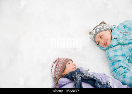 Mädchen im Schnee liegend Stockfoto