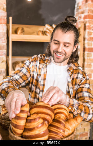 Stattliche Verkäufer setzen Gebäck in Weidenkorb Stockfoto