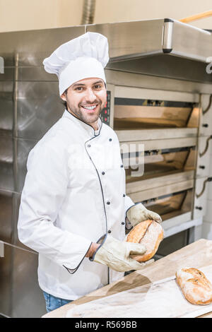 Lächelnd Bäcker, Köche einheitliche Holding frisches Brot in der Nähe von Ofen Stockfoto
