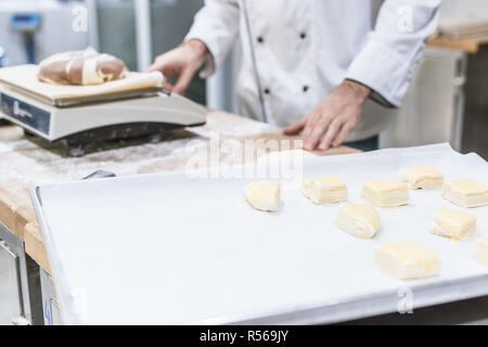 7/8-Ansicht von Baker wiegen Teig auf Küchenwaagen Stockfoto