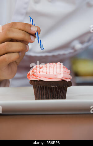 Person die Kerze auf cupcake Stockfoto