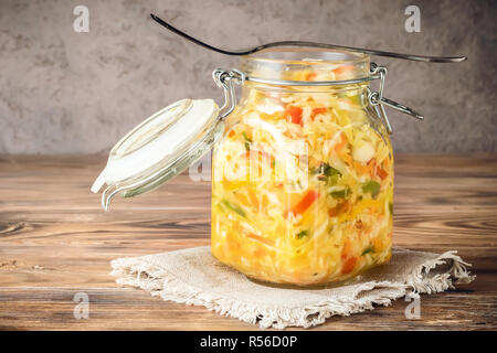 Salat Vorspeise von fermentierten Gemüse Sauerkraut Karotten und Paprika in Glas Glas mit Deckel und Gabel auf rustikalen Holzmöbeln Hintergrund. Konzept trend Diät Stockfoto