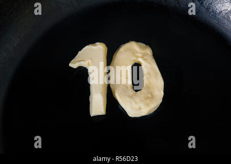 Butter in Form der Zahl 10 auf heiße Pfanne - Nahaufnahme, Ansicht von oben Stockfoto