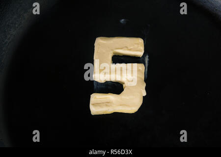 Butter in Form der Zahl 5 auf heiße Pfanne - Nahaufnahme, Ansicht von oben Stockfoto