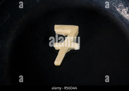 Butter in Form der Zahl 7 auf heiße Pfanne - Nahaufnahme, Ansicht von oben Stockfoto