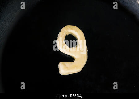 Butter in Form der Zahl 9 auf heiße Pfanne - Nahaufnahme, Ansicht von oben Stockfoto