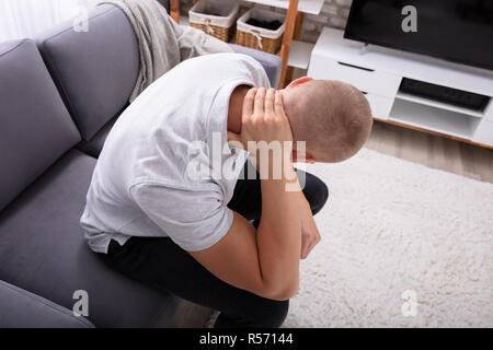 Close-up ein Mann sitzt auf einem Sofa leiden unter Nackenschmerzen Stockfoto
