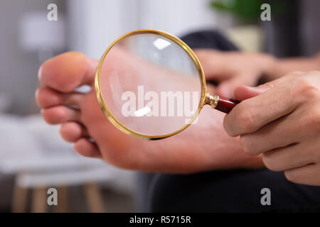 Close-up In eines Mannes Hand mit Lupe vor seinen Füßen Stockfoto