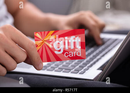 Mann mit roten Karte beim Tippen auf Laptop Tastatur Stockfoto