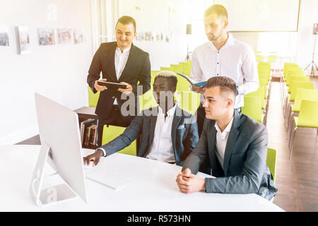 Gruppe von Unternehmern, die Arbeiten mit einem Laptop und halten ein Dokument Stockfoto