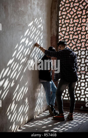 Zwei Jungs in das Smartphone vor dem Marmor lattice mihrab von Humayun's Grabmal, Delhi, Indien Stockfoto