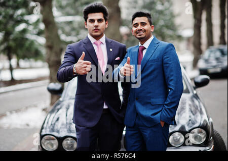 Zwei elegante indischen Modische mans Modell auf, am Winter Tag gegen Schwarz classic car gestellt und zeigt den Daumen nach oben. Stockfoto