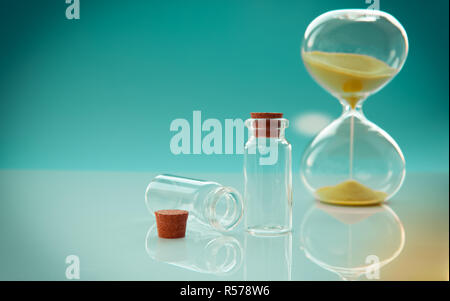 Leere Flaschen mit Kork Stopper und Sanduhr auf Getöntem Hintergrund, Nahaufnahme Stockfoto