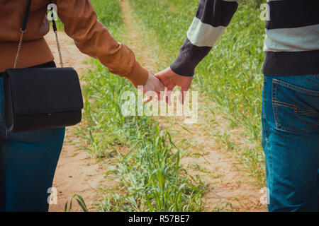 Junges Paar Hand in Hand auf dem Hintergrund des grünen Grases Stockfoto