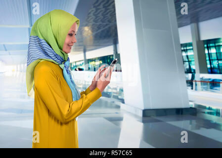 Hübsche asiatische muslimischen Frau, Ihr Mobiltelefon zu berühren Stockfoto