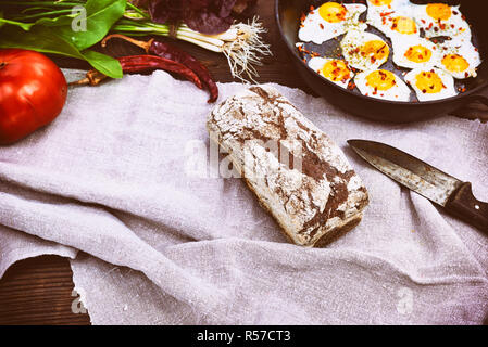 Laib Schwarzbrot und gebratene Eier in eine Schwarze Pfanne Stockfoto