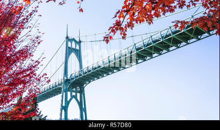 Beliebte gothic St Johns Brücke mit Dunst über den Willamette River in Portland im industriellen Bereich mit gewölbten Stützen im Herbst rot umgeben Stockfoto