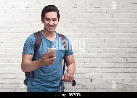 Junge asiatischer Mann reise mit Handy mit Koffer Stockfoto