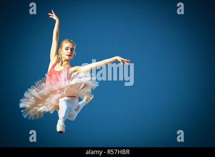 Schöne weibliche Ballett-Tänzerin auf einem grauen Hintergrund. Ballerina trägt rosa Tutu und Pointe Schuhe. Stockfoto