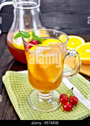 Limonade mit Kirschen in wineglass und Kanne auf dunklen Kammer Stockfoto