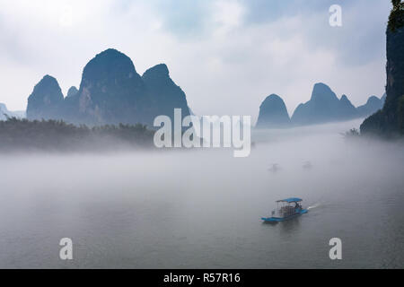 Anzeigen von Nebel mit Schiffen auf dem Fluss in der Nähe der Stadt Xingping Stockfoto