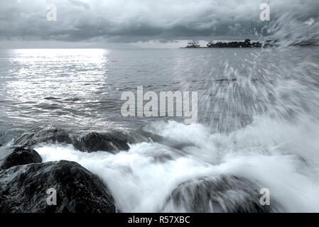 Wellen Spritzen auf einem natürlichen Felsen an der Küste. Schwarz und Weiß. Stockfoto