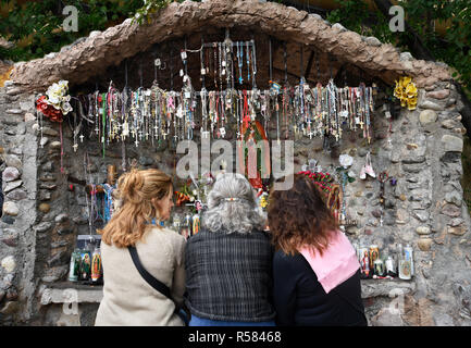 Drei Frauen sitzen vor einem Schrein neben El Santuario De Chimayo in der spanischen Dorf Chimayo, New Mexico. Stockfoto