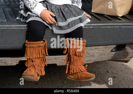 Ein Mädchen mit Fransen Stiefel sitzt im Bett der Pickup Truck ihrer Eltern in dem kleinen spanischen Dorf Chimayo in New Mexiko. Stockfoto