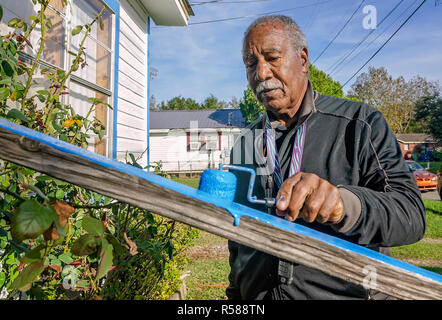 New York Mets Hall of Fame Cleon Jones malt ein Verandgeländer für eine Witwe in Africatown, 21. November 2018, in Mobile, Alabama. Stockfoto