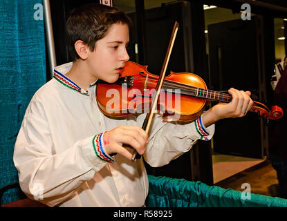 Ein Junge in der traditionellen russischen Kleidung spielt eine Violine auf der 34. jährlichen Mobile International Festival, Nov. 17, 2018 in Mobile, Alabama. Stockfoto