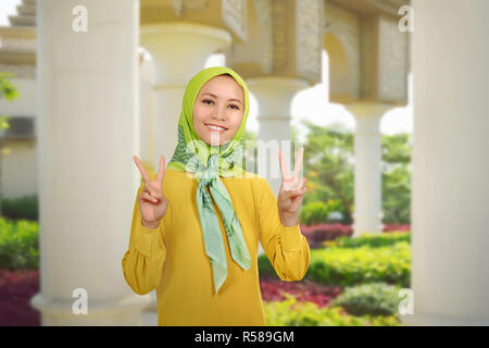 Schöne asiatische muslimische Frau mit zwei Fingern Stockfoto