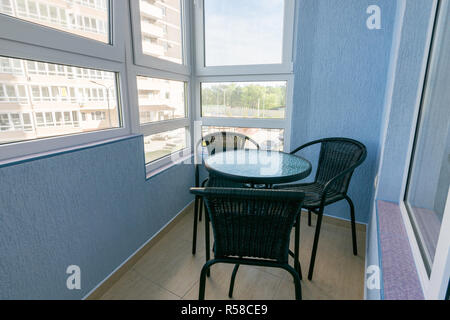 Ein Tisch und drei Stühle auf dem Balkon in der Wohnung eines mehrstöckigen Mehrfamilienhauses Stockfoto