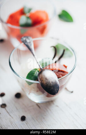 Eis Schaufeln mit Kirsche Frucht, Schokolade, Karamell, Vanille und Minze auf weiße Holztisch von oben. Retro Filter. Stockfoto