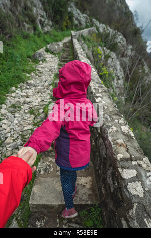 Kleine Mädchen, dass ihr Vater und ihn Führenden auf einem steilen Schritte auf einem Wanderweg auf den Berg Trail Stockfoto