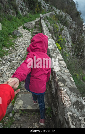 Kleine Mädchen, dass ihr Vater und ihn Führenden auf einem steilen Schritte auf einem Wanderweg auf den Berg Trail Stockfoto