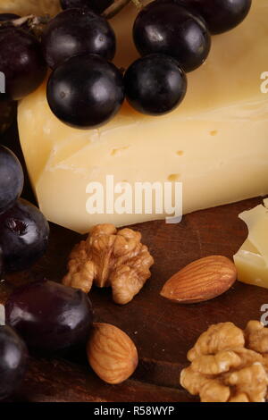 Greyerzer Käse auf einem Holztisch mit Trauben, Nüssen und Olivenöl Stockfoto