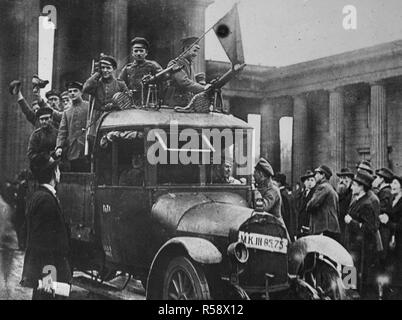 Deutsche Revolution - die Deutsche Revolution. Ein Motor der Arbeiter und Soldaten "Rat vorbei am Brandenburger Tor in Berlin. Der Motor ist mit einem Maschinengewehr bewaffnet und Flied die rote Flagge. Es führt auch eine Wache, bewaffnet mit einem Gewehr Ca. 1918-1919 Stockfoto