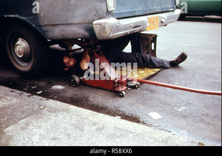 1974 - Mann bei der Arbeit auf dem Auto in Hell's Kitchen, New York City... 06/1974 Stockfoto