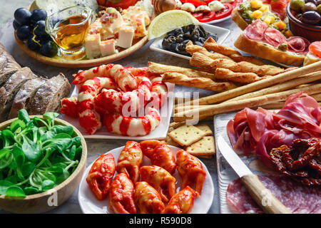 Italienische Antipasti Snacks. Brushettas, Käse Vielfalt, Garnelen, Lachs, Oliven, Schinken mit Birne, Salami und Schinken über Graues grunge Tabelle, oben Stockfoto