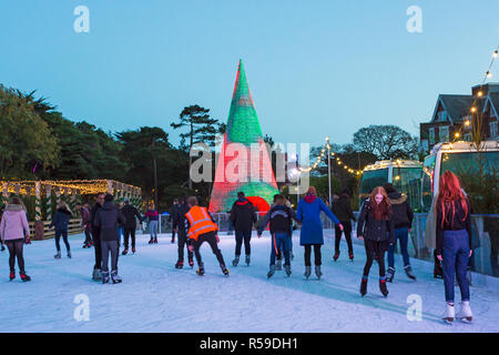 Bournemouth, Dorset, Großbritannien. 25 Nov, 2018. Besucher genießen Schlittschuhlaufen auf der Outdoor eislaufen Eisbahn in Bournemouth untere Gärten in Bournemouth im November, im Freien Eislaufbahn. Dahinter ist der Bournemouth Wunderland Baum, Teil der Bournemouth Weihnachtsbaum Wunderland, eine exemplarische Vorgehensweise Baum stehend 60 Fuß hoch und die Farbe ändert. Credit: Carolyn Jenkins/Alamy leben Nachrichten Stockfoto