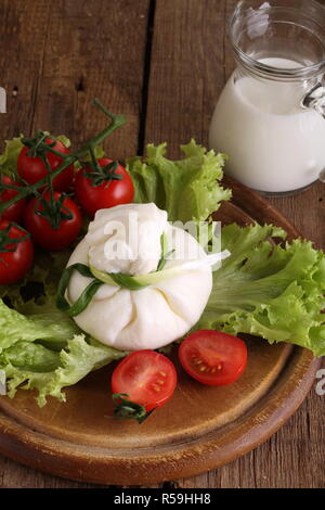 Burrata mit Tomaten und Sahne auf Salatblättern Stockfoto