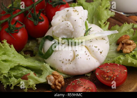 Burrata mit Tomaten und Sahne auf Salatblättern Stockfoto