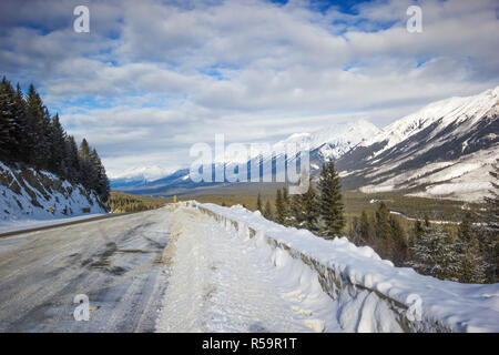 Schmalen und rutschigen Winter Straße mit großen Snowbanks geschwungene von Berg, Banff National Park, Kanada Stockfoto