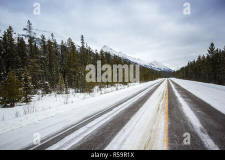 Lange leer Winter Straße, die zu den Bergen, Banff National Park, Kanada Stockfoto