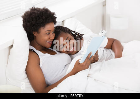 Mutter und Kind ein Buch lesen im Bett Stockfoto