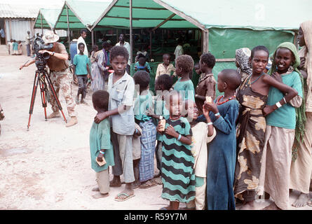 1993 - Der Chief Fotograf Mate Robert Sasek Videobänder Somalis Futter für eine Mahlzeit an der Sorge der Fütterung während der multinationalen Entlastung Bemühung Operation Restore Hope. Das Zentrum wird von der irischen Hilfsorganisation Sorge betrieben. Stockfoto