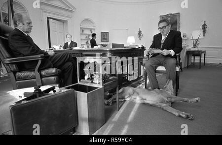 November 16, 1974 - Oval Office - das Weiße Haus Gerald R. Ford, Henry A. Kissinger, Brent Scowcroft, Freiheit der Hund - um Schreibtisch sitzen, reden; Freiheit liegt am Fuß der Kissinger; PET-Golden Retriever Stockfoto