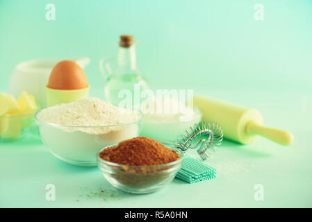 Bäckerei Essen, kochen Konzept. Andere Backzutaten - Butter, Zucker, Mehl, Milch, Eier, Öl, Löffel, Nudelholz, Pinsel, Schneebesen über Blau b Stockfoto
