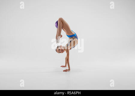 Die jugendlich weiblich Mädchen Gymnastik Übungen isoliert auf einem grauen studio Hintergrund. Die Gymnastik, Dehnen, Fitness, Lifestyle, Ausbildung, Sport Konzept Stockfoto