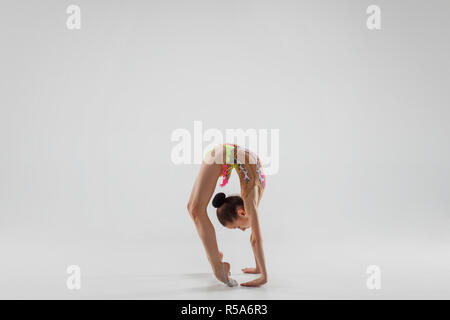 Die jugendlich weiblich Mädchen Gymnastik Übungen isoliert auf einem grauen studio Hintergrund. Die Gymnastik, Dehnen, Fitness, Lifestyle, Ausbildung, Sport Konzept Stockfoto